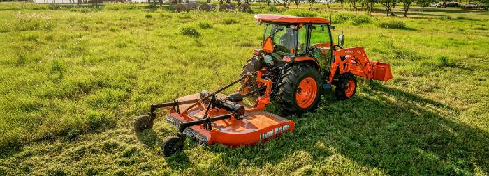 Kubota MX Series tractor with a loader and rotary cutter working a field