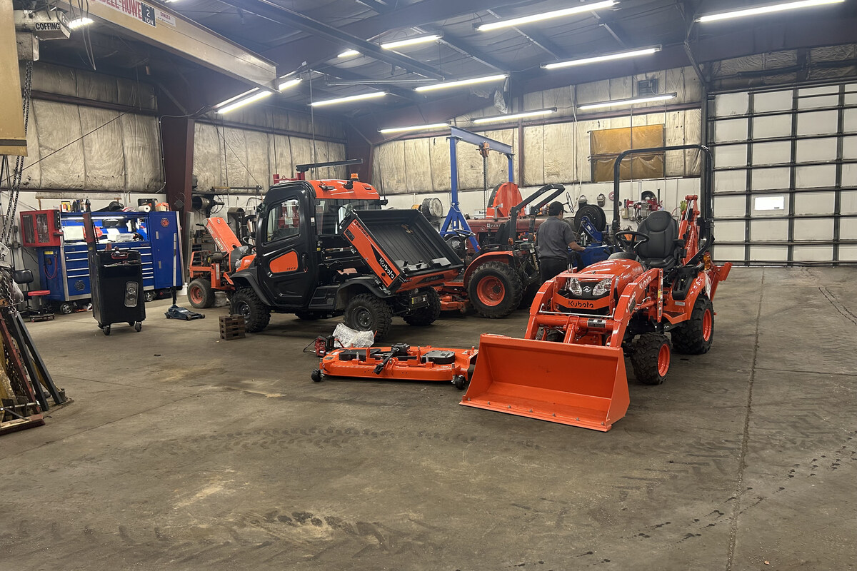 Unkefer Sales service bay with Kubota tractors, an RTV, and a technician at work